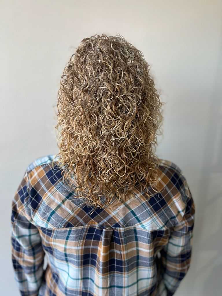 Person with curly hair from behind wearing a plaid shirt.