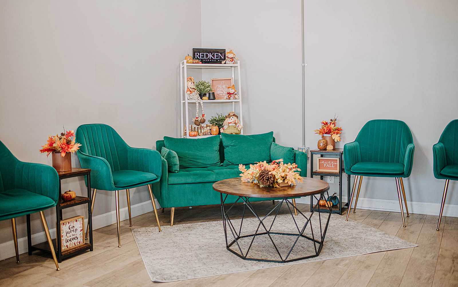 Cozy waiting area with green chairs, fall decorations, and a coffee table with flowers.